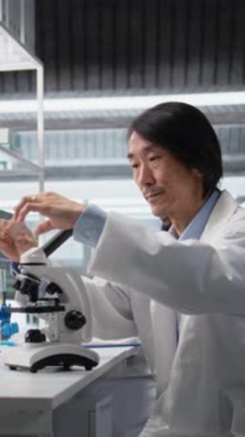 Man in Lab Coat Using Microscope in Lab