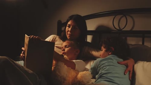 Mother Reads Bedtime Story to Children in Bed