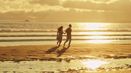 Romantic Couple Walking on Beach at Sunset