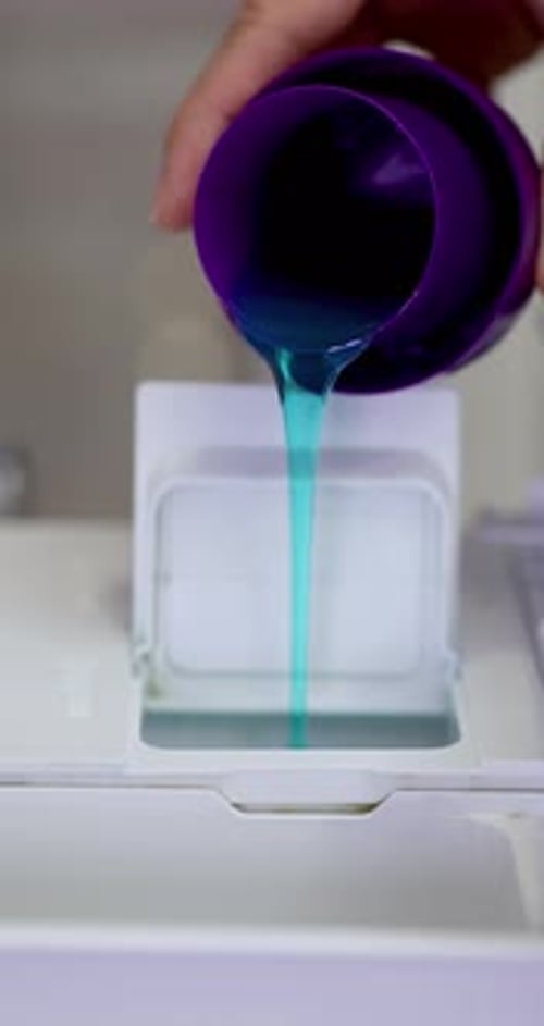 Blue Detergent Liquid Poured into Machine Dispenser Compartment