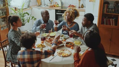 Family Gathering Toasts at Festive Meal in Kitchen