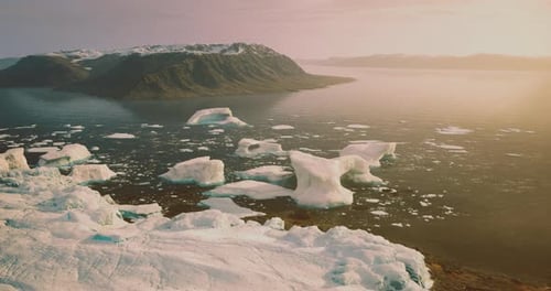 Sunrise Over Icy Landscape with Floating Icebergs Near Rugged Coastline