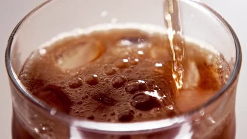 Brown Fizzy Drink being Poured Over Ice