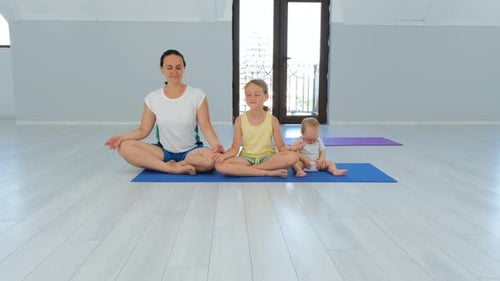 Mother with Children Doing Yoga in Fitness Hall