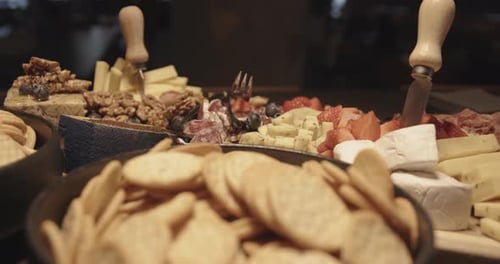 Close up of cheese and charcuterie platter on buffet at party, bowls with crackers