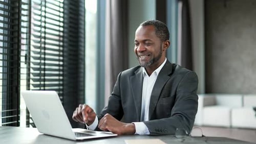 Smiling Man Working on Laptop in Bright Workplace