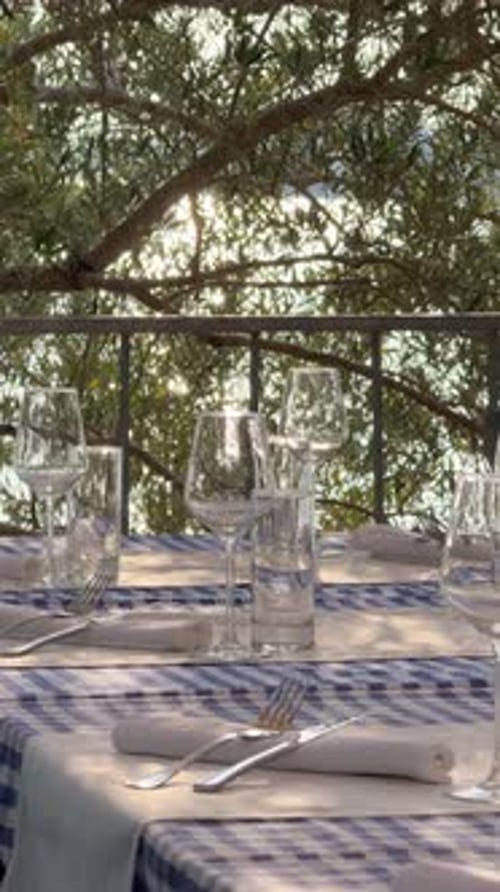 Close Up of a Beautifully Set Restaurant Table with Glassware and Plates In the Background Sunlight