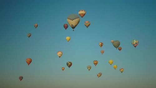 Large collection of hot air balloons drifting in front of blue sky