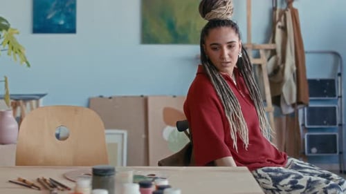 Female Artist with Disability Choosing Paints in Her Studio