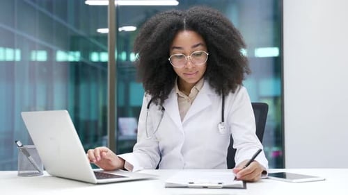 Young Adult Doctor Working at Desk in Modern Office