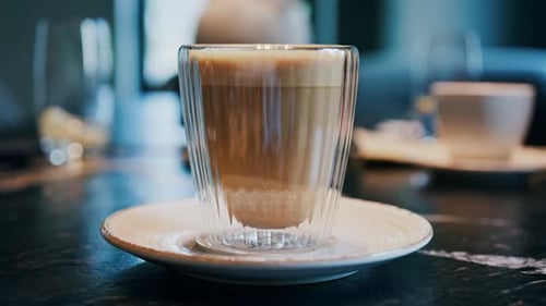 Close up of a glass cup with a latte at a cafe