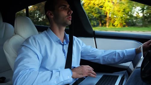 Male Businessman Typing Text on Laptop During Riding on Electrical Vehicle with Autopilot Handsome