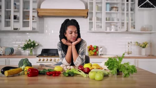 Pensive Woman with Fresh Vegetables in Modern Kitchen