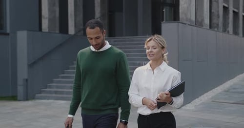 Businesspeople Discussing Business Plans with Each Other While Walking Outside at the Street