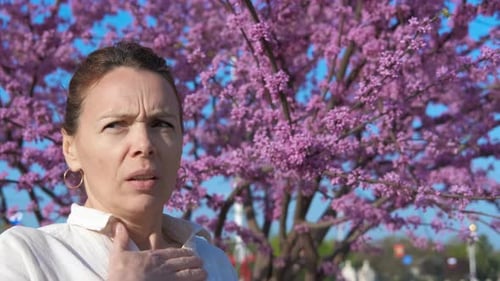 Woman Using Inhaler with Spring Tree Background