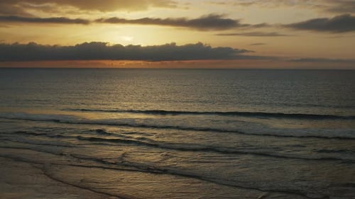 Beach of the Atlantic Ocean at sunset. Sun reflected on the water surface.