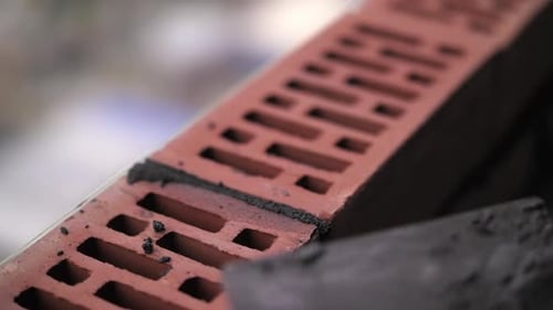 Um pedreiro coloca uma parede de tijolos vermelhos