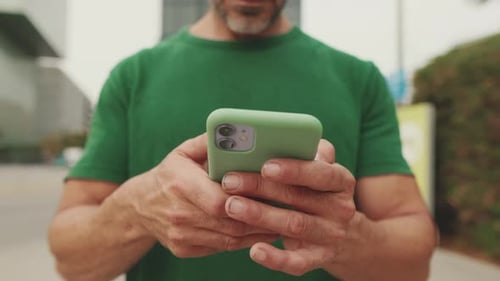 Close-up, hands of an unrecognizable middle-aged man using mobile phone outside on the street