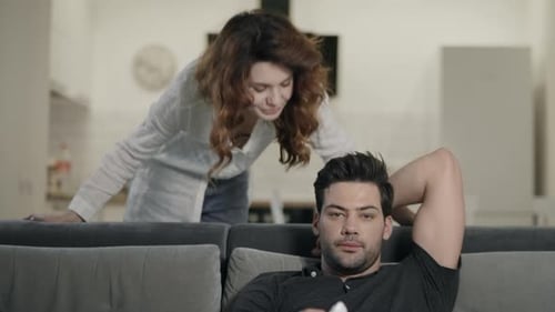 Man Relaxing on Couch with Woman in Background