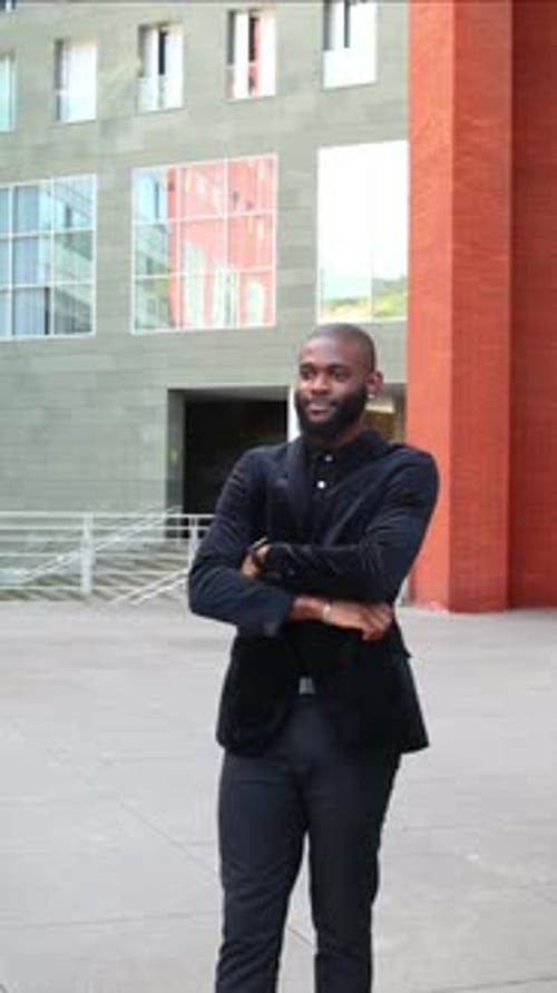 vertical Triumphant black African businessman in suit crossing arms in financial district