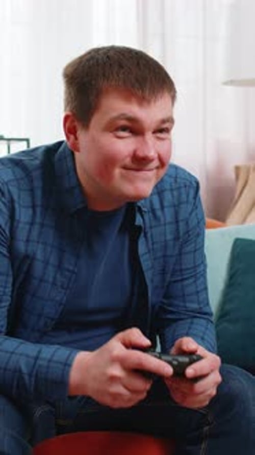 Man playing video games, celebrating success at home