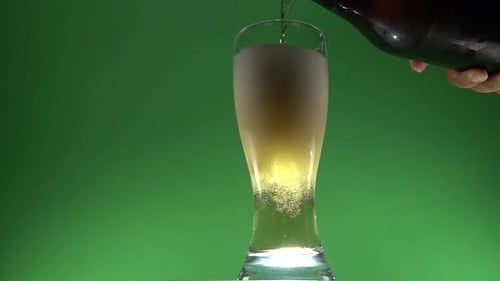 Pouring Refreshing Beer into Glass on Green