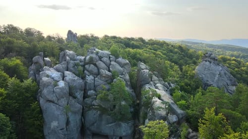 Luftaufnahme einer hellen Landschaft mit grünen Waldbäumen und großen Felsbrocken zwischen dichten Wäldern