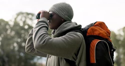 Homem negro, binóculos e mochila em viagem para explorar, passear ou procurar um caminho