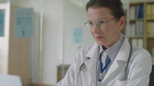 Female Doctor Working on Laptop at Office Desk