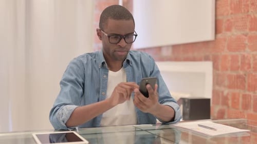 Hombre africano que usa un teléfono inteligente en el trabajo