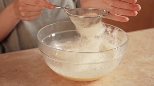 Frau sitzt zu Hause in der Küche am Tisch und bereitet Teig für das Waffelfrühstück zu