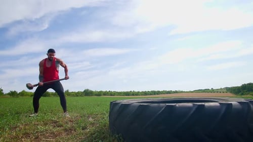 Un homme musclé fait preuve de force en heurtant un pneu au Crossfit Training Outdoors Slowmo