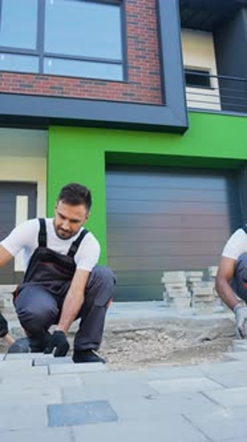 Two Diverse Construction Workers Fixing the Pavestone on Patio