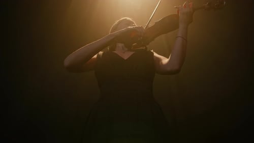 Woman Performs Intense Violin Solo in Dramatic Lighting
