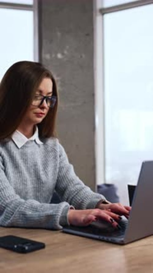 Woman Typing on Laptop in Office Environment
