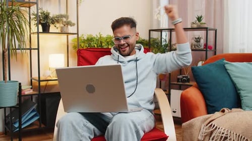 Man Celebrates Good News on Laptop at Home