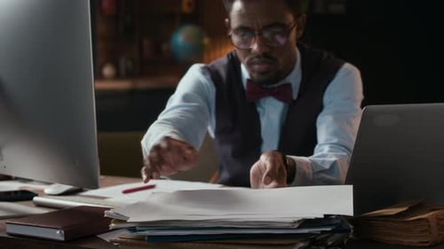Man Sorting Documents at Desk in Office