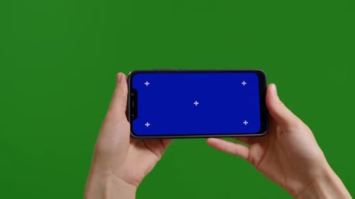 Female blue chroma key screen on smartphone device on green screen background.