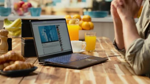 Man Watches Video on Laptop During Kitchen Breakfast