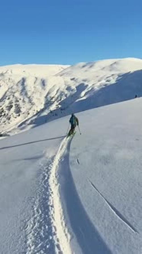 Skier Gliding Down a Pristine Snowy Mountain Slope on a Sunny Day Enjoying OffPiste Freeride