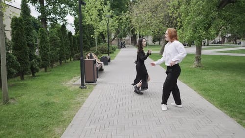 A Man and Woman Dance Joyfully in a Lively Park Celebrating