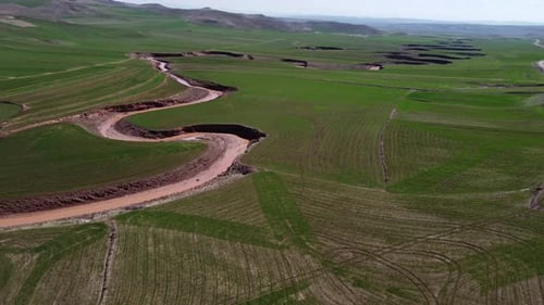 Aerial view of the river running through the fields in the vast land 4K