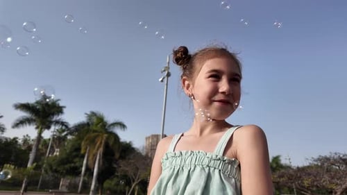 Little Girl Playing with Soap Bubbles in Golden Sunlight