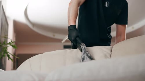 Man Cleaning Couch with Vacuum Cleaner