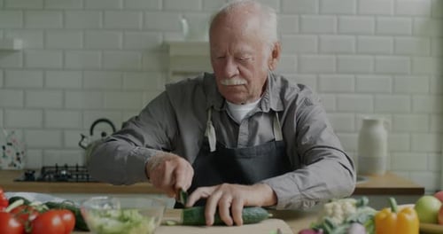 Senior Man Dicing Cucumber in Bright Kitchen