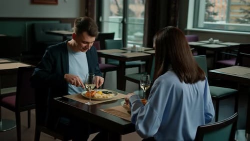Date in the hotel restaurant dinner man and woman drink white wine in glasses and taste food