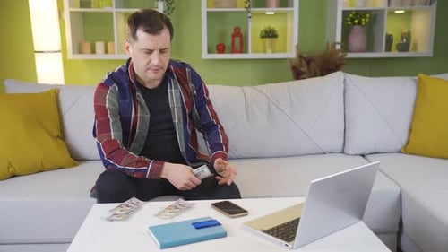 Man Counting Cash on Sofa in Living Room
