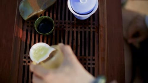 Hand Man Tea Maker Pouring Green Tea in Small Bowls on on Wooden Table Chaban