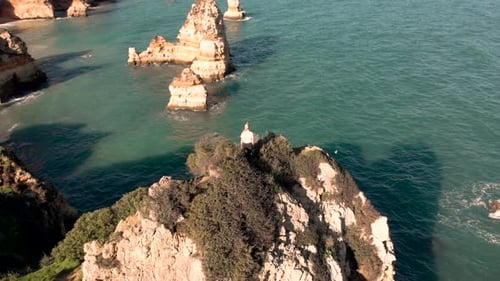 AERIAL: Girl is standing on the cliffs in Portugal enjoying a beautiful view