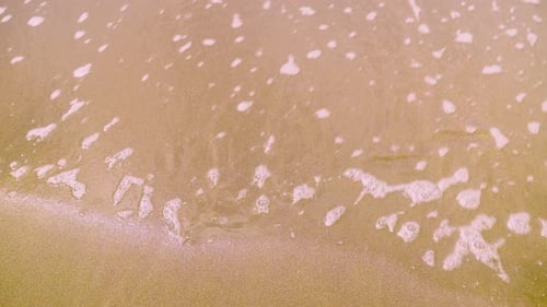 Wave of water washes away inscription 2022 on sand. concept of new year